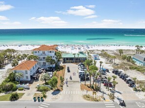 Un hotel sulla spiaggia con parcheggio, l'edificio principale e una struttura più piccola.