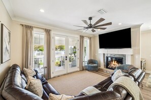 A living room with a fireplace, leather sofas, a flat-screen TV, and a ceiling fan. - Luxury New Build • Steps From The Beach • Pool • Sleeps11 (Destin)