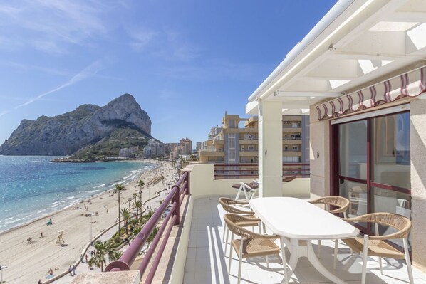A balcony with a table and chairs overlooking a beach and a mountain. - Topacio 18 - Costa CarpeDiem (Calpe)