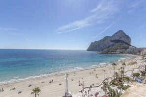 A beach with a rocky outcrop, clear blue water, and a promenade with palm trees. - Topacio 18 - Costa CarpeDiem (Calpe)