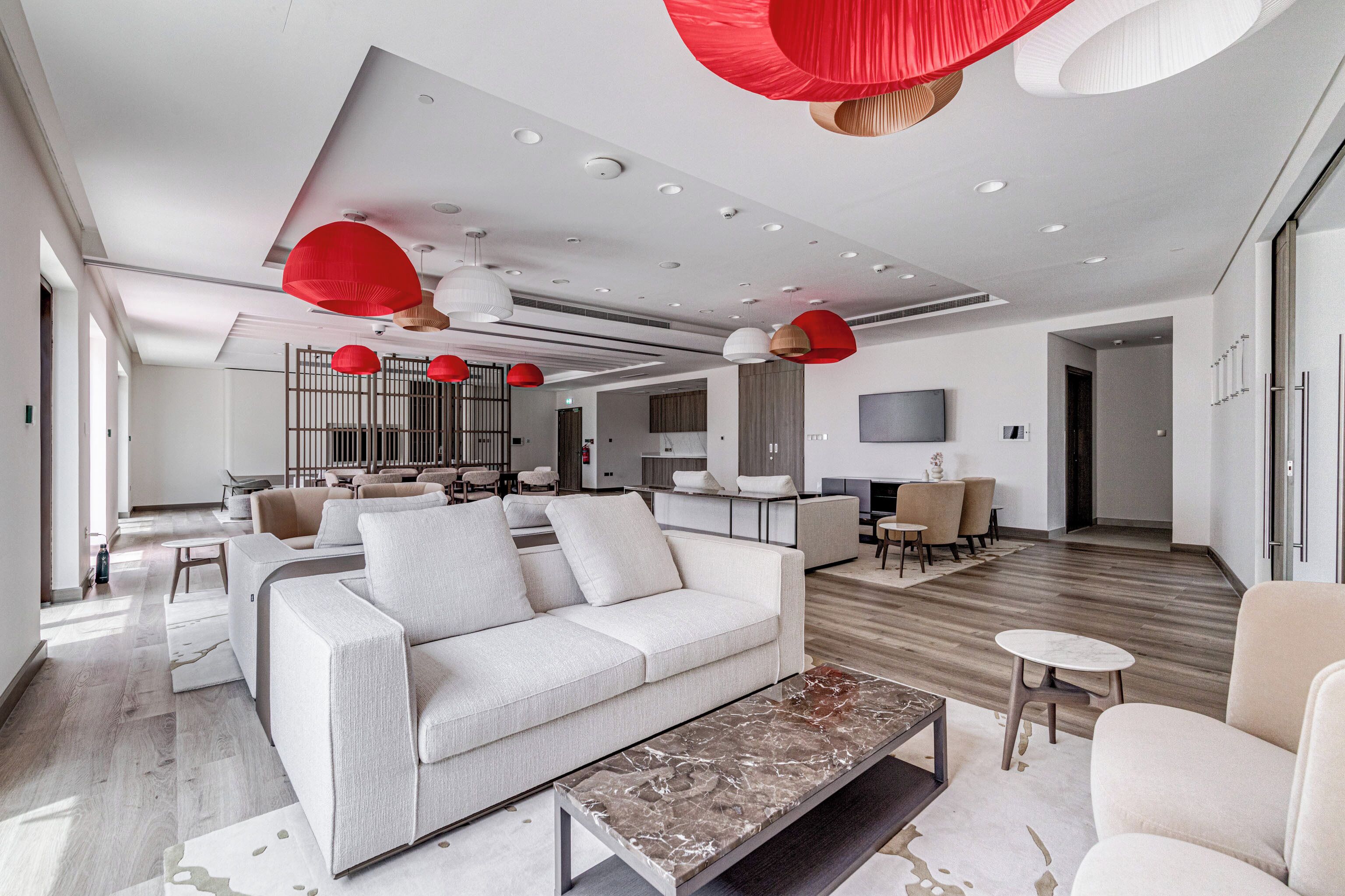 A modern living room with a sofa, coffee table, and red pendant lights.
