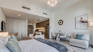 Una habitación de hotel moderna con una cama grande, un sofá, una mesa de comedor y una cocina.