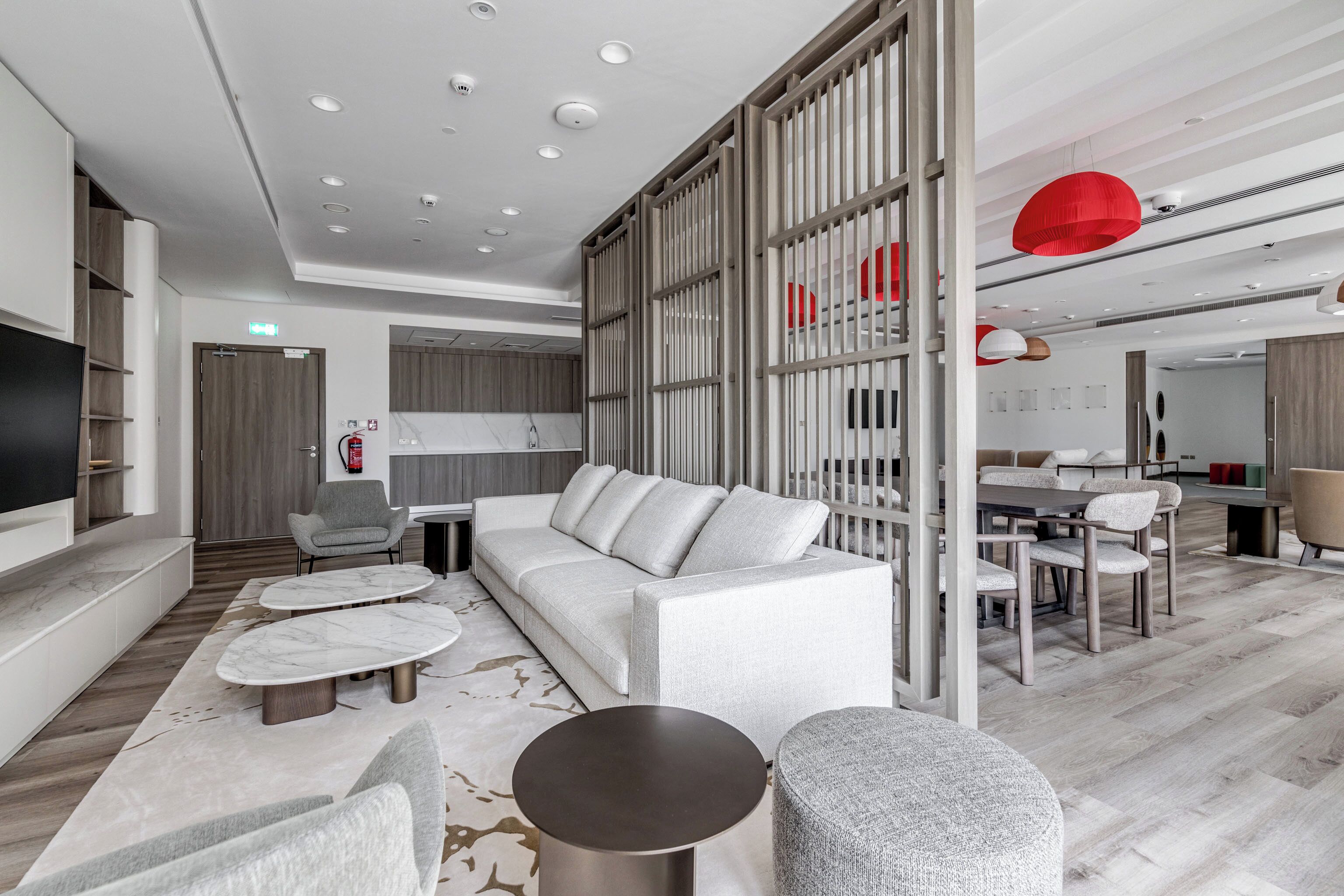 A modern living room with a sofa, coffee table, ottoman, and a dining area with chairs and a table.