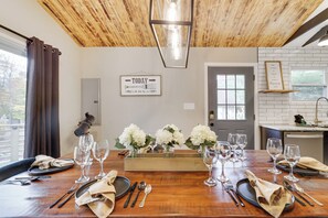 A dining table set with wine glasses, plates, and cutlery, a wooden ceiling, and a sign on the wall. - Harmony Hideaway- Your Perfect Pocono Retreat-Pet Friendly with Hot Tub (Lake Harmony)
