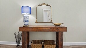 A wooden console table with a blue and white ceramic lamp, a gold-framed mirror, and a brass bowl. - Full apartment rental with a balcony downtown. Park and walk to everything. (Ocean Springs)