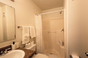 A bathroom with a sink, toilet, shower, and a mirror. - New Cozy Studio Fast WiFi & Work Desk (Tolleson)