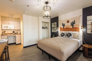 A modern bedroom with a bed, a desk, a microwave, and a closet. - New Cozy Studio Fast WiFi & Work Desk (Tolleson)