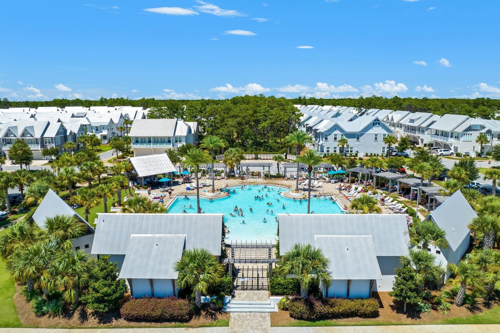 A resort with multiple buildings, a central swimming pool, and palm trees.
