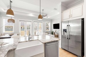 Eine moderne Küche mit einem Edelstahl-Kühlschrank, Granit-Arbeitsplatten und Pendelleuchten.