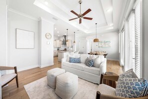 A spacious living room with a white sofa, ottomans, and a ceiling fan. - Big Chill Bungalow @ Prominence On 30a- walk to the Big Chill- 4 Bikes Provided (Inlet Beach)