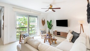 A living room with a ceiling fan, a large window with a view, a flat-screen TV, and a sofa. - Apartment central 8 pax tendenza, 2 rooms and with services included. (Playa del Carmen)