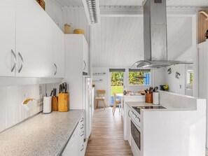 Eine moderne Küche mit weißen Schränken, einer zentralen Kochinsel und Blick ins Freie.