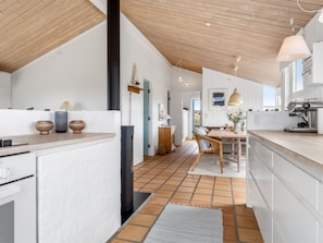 Eine moderne Küche mit weißen Schränken, einer Holzbalkendecke und einem Essbereich mit Tisch und Stühlen.