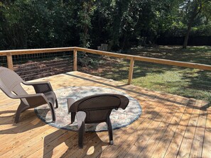 A wooden deck with two wicker chairs and a patterned rug. - Cozy sunny 1-bedroom cottage in Decatur. (Decatur)