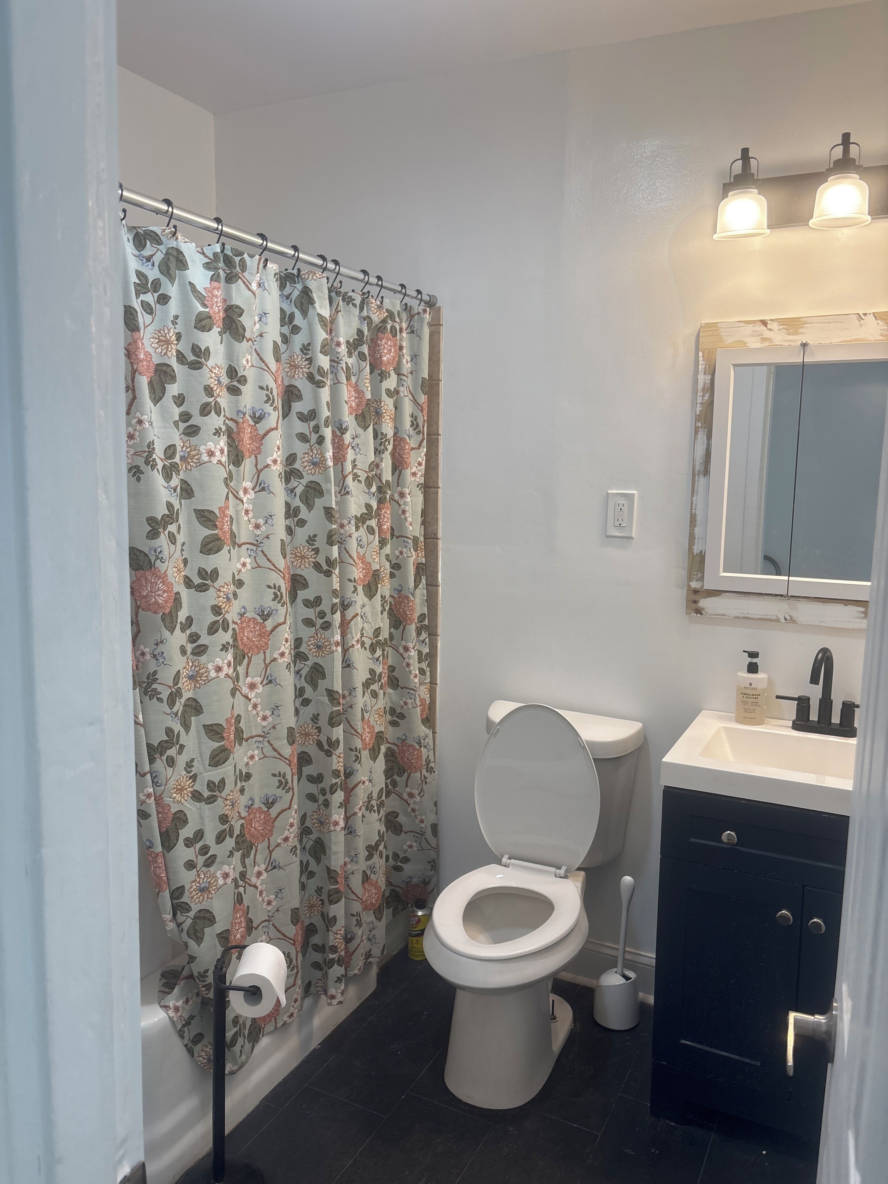 Un baño con inodoro, lavabo, cortina de ducha y un espejo sobre el lavabo.
