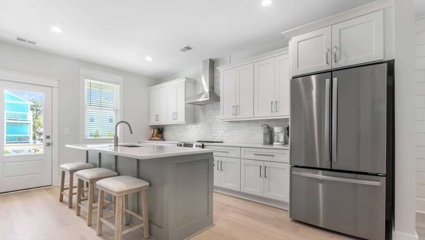 Una cocina moderna con una isla central, electrodomésticos de acero inoxidable y armarios de tonos claros.