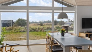 A modern interior with a large dining table, chairs, a hanging light fixture, and a TV mounted on the wall. - "Minka" - 500m from the sea by Interhome (Blokhus)