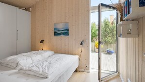 A modern bedroom with a bed, a painting, a wardrobe, and a door leading to an outdoor area. - "Minka" - 500m from the sea by Interhome (Blokhus)
