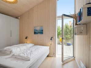 Ein modernes Schlafzimmer mit Bett, einem Gemälde, einem Kleiderschrank und einer Tür zu einem Außenbereich.