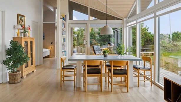 A dining area with a large table and chairs, a hanging light fixture, and a view of the outdoors. - "Minka" - 500m from the sea by Interhome (Blokhus)