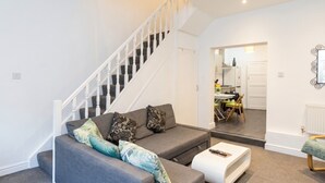 A living room with a grey sofa, a white coffee table, and a staircase leading to another room. - Mezzanine loft cottage steps from LGI and the city centre (West Yorkshire)