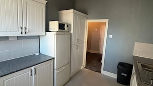 Una cocina con armarios blancos, un microondas y un refrigerador.