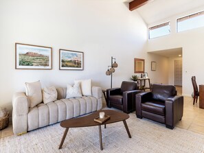 A living room with a sofa, two armchairs, a coffee table, and framed artwork on the wall. - Gorgeous 2 BR Condo with Golf Views & Fire Pit (Palm Desert)
