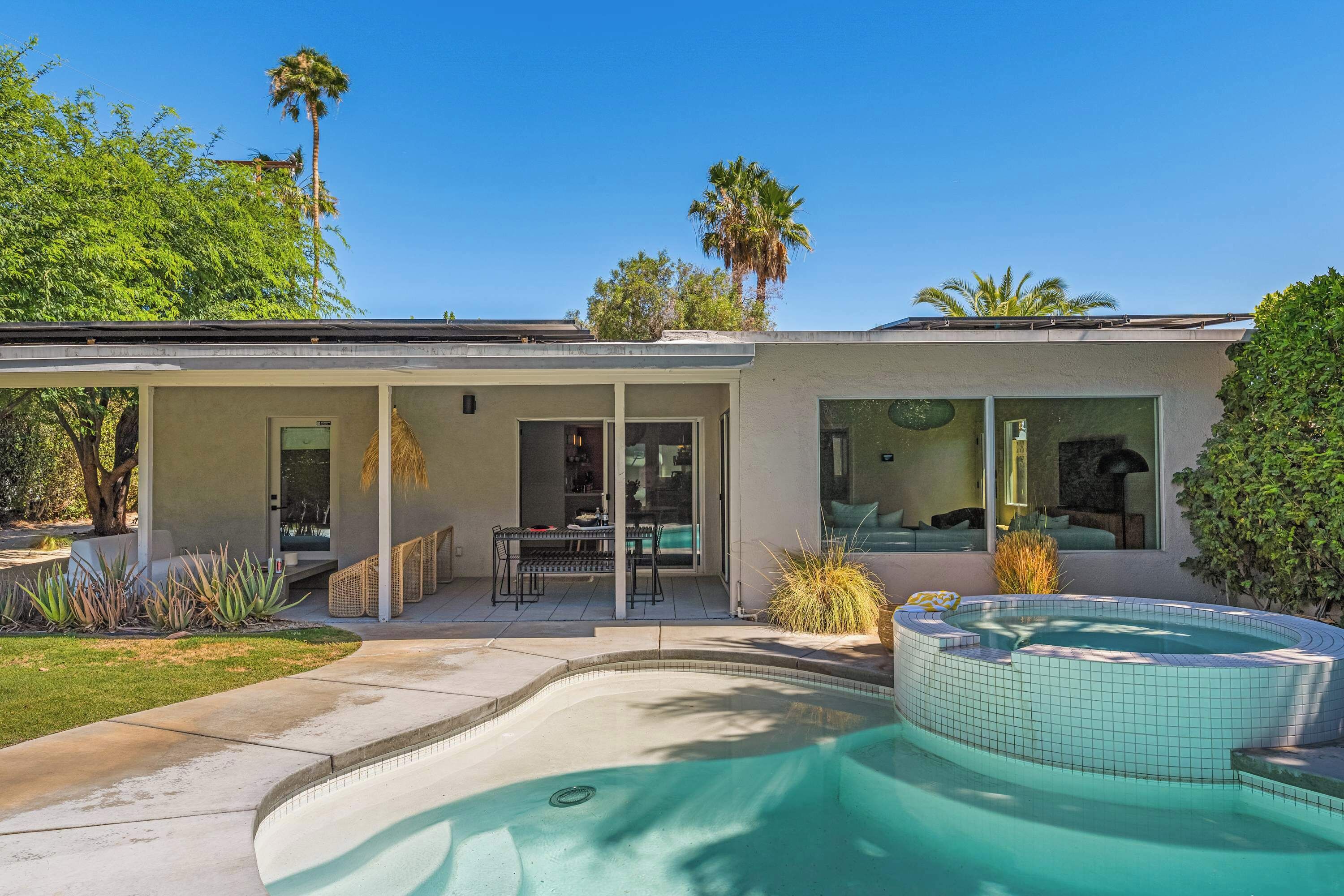 A modern house with a swimming pool, patio, and a covered outdoor seating area.