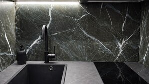 A modern kitchen with a black sink, faucet, and matching countertop. - The Aegean Pearl Athens by ΜΡS (Kallithea)