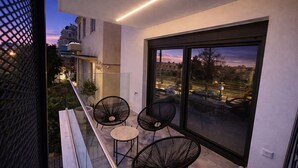 A balcony with chairs, a railing, and a view of the cityscape at dusk. - The Aegean Pearl Athens by ΜΡS (Kallithea)