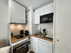 A compact kitchen with white cabinets, a microwave, a coffee maker, and a sink. - 1st floor, balcony, tv, ski locker, 20m², Vars (Vars)