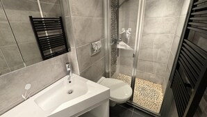Een badkamer met douche, toilet en wastafel.