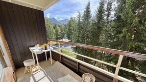Een balkon met een tafel, stoelen en een rieten mand.