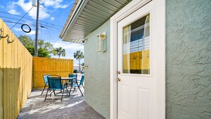A patio with a table and chairs, a door, and a wooden fence. - Opalite on Sunset | Pink Beach Retreat (Panama City Beach)