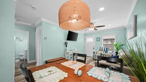 A dining area with a wooden table, chairs, a woven pendant light, and a ceiling fan. - Sun Kissed Cheeks w/ Fire Pit & Beach Gear (Panama City Beach)