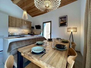 A modern kitchen with wooden cabinets, a dining area with a wooden table and chairs, and pendant lighting. - 4th floor, terrace, tv, 80m², Serre Chevalier (Briançon)