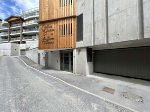 A building with a wooden facade, a garage door, and a concrete structure. - 4th floor, terrace, tv, 80m², Serre Chevalier (Briançon)