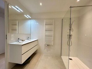 A modern bathroom with a glass shower enclosure, white vanity with dual sinks, and a large mirror. - 4th floor, terrace, tv, 80m², Serre Chevalier (Briançon)