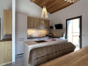 A modern kitchen with wooden cabinets, a central island with seating, and a pendant light. - 4th floor, terrace, tv, 80m², Serre Chevalier (Briançon)