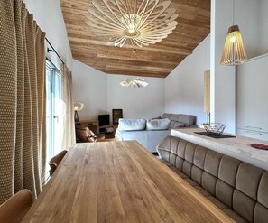 A modern interior with a wooden dining table, a sofa, and a unique ceiling light fixture. - 4th floor, terrace, tv, 80m², Serre Chevalier (Briançon)