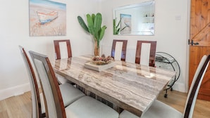 Een eetkamer met een marmeren tafel, stoelen, kunstwerken en een spiegel.