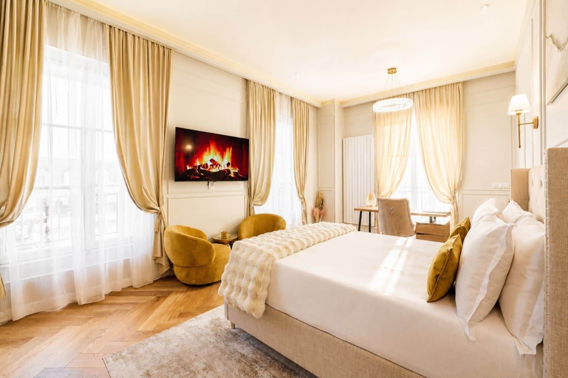 Ein Hotelzimmer mit einem großen Bett, einem an der Wand befestigten Fernseher, einem Schreibtisch und einem Stuhl.