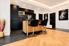 A modern kitchen with a black countertop, two black bar stools, a microwave, and a wine glass. - Majesticpearl 65sqm - Balneo - Station -Parking (Amiens)