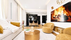 Ein Wohnzimmer mit einer Couch, Sesseln, einem Couchtisch und einem Kamin mit Feuer.
