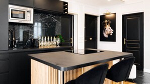 Eine moderne Küche mit integriertem Mikrowellenherd, Marmor-Spritzschutz und einer Bar, komplett mit Flaschen und Gläsern.