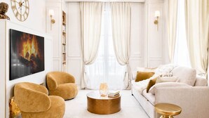 Un salon comprenant un canapé, des fauteuils, une table basse, un téléviseur et une cheminée.