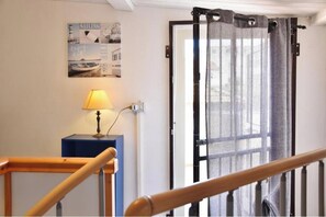 Eine Treppe mit Holzhandlauf, eine Lampe auf einem blauen Tisch und eine Tür mit grauem Vorhang.