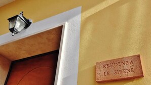 A door with a circular design, a wall-mounted light fixture, and a plaque reading 'RESIDENZA LE SIRENE'. - Residenza Le Sirene - Holiday Home with Jacuzzi and Terrace near Tropea (Santa Domenica)