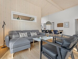 Ein modernes Wohnzimmer mit einem grauen Ecksofa, einem Couchtisch und schwarzen Ledersesseln.