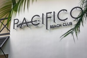 Eine Wand mit dem Schriftzug 'PACIFICO BEACH CLUB' und einem Palmenblatt-Design.